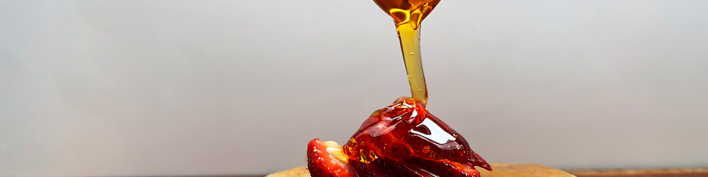 Raw honey poured over strawberries and pancakes