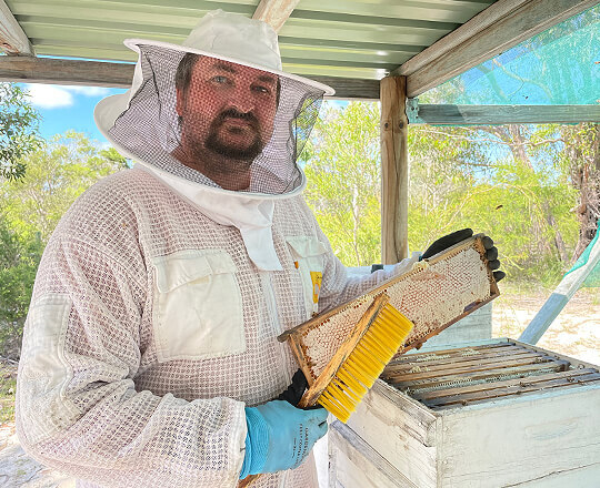 An owner of Goodwood Produce, Will, opening the beehive