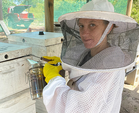 Kylie using bee smoker prior to opening bee hive